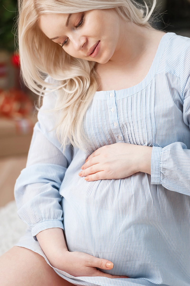 Schwangere Frau umfasst liebevoll ihren Bauch